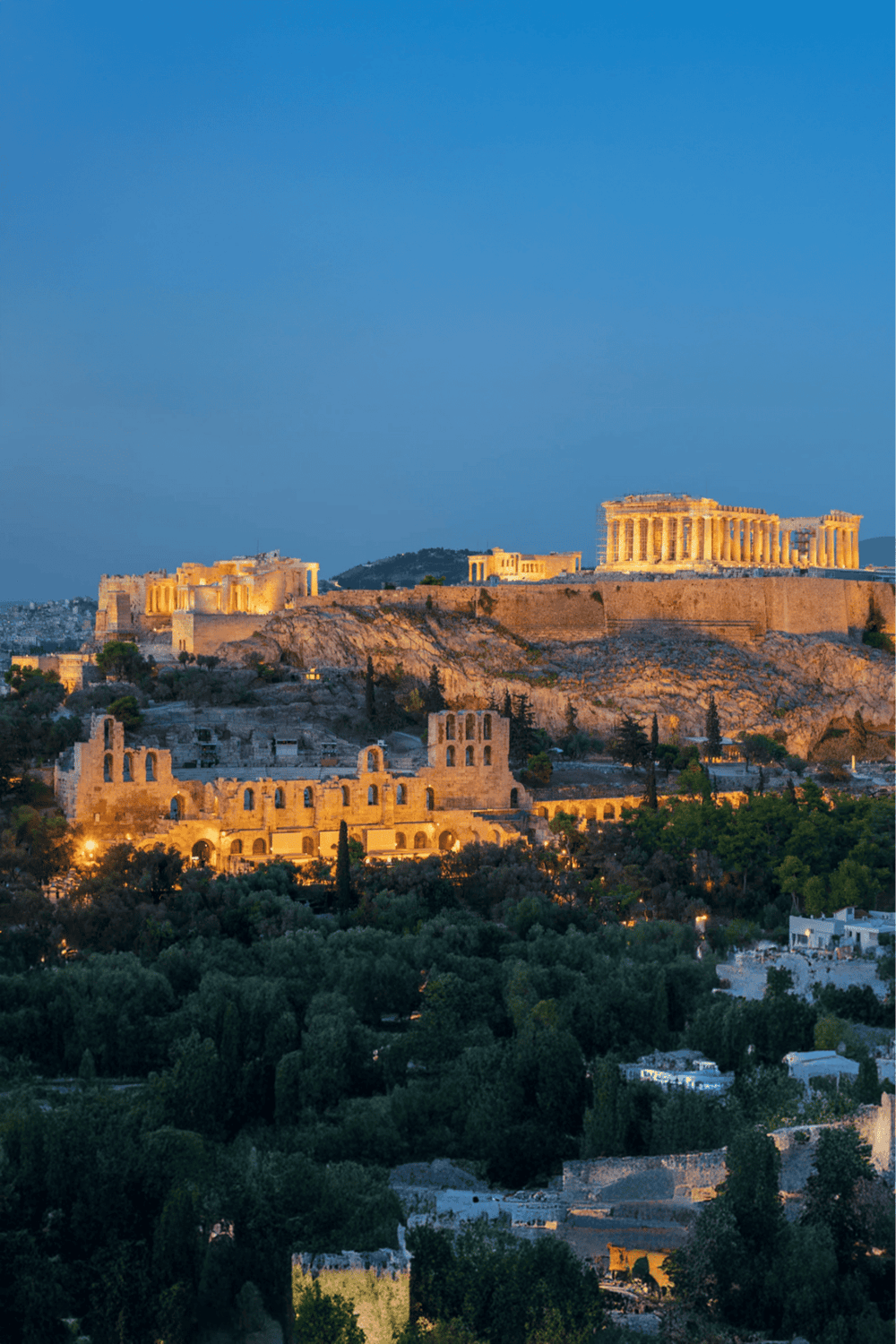 Ancient Greek ruins with the Acropolis of Athens illuminated at dusk, showcasing historic landmarks and scenic city views.