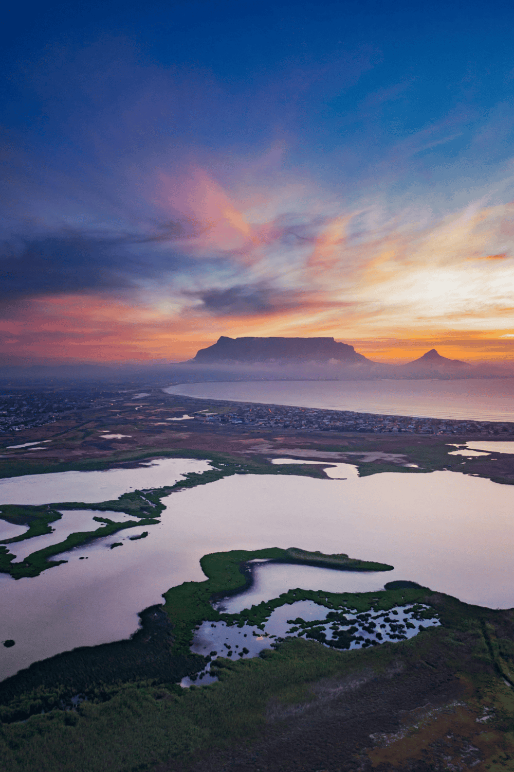 Scenic aerial view of Table Mountain and surrounding wetlands at sunset in Cape Town, South Africa, showcasing natural beauty and outdoor adventure.