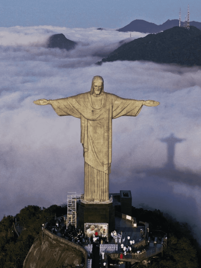 Statue of Christ the Redeemer overlooking clouds in Rio de Janeiro, Brazil. Iconic landmark with scenic mountain views.