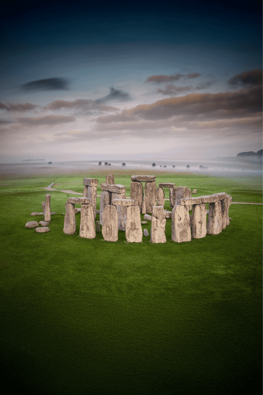 Ancient Stonehenge with dramatic sunset sky and lush green landscape, iconic prehistoric monument, England attraction.