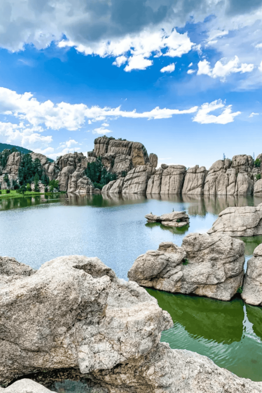 Serene mountain lake with rocky cliffs and blue sky, perfect for outdoor adventures and Nature exploration.