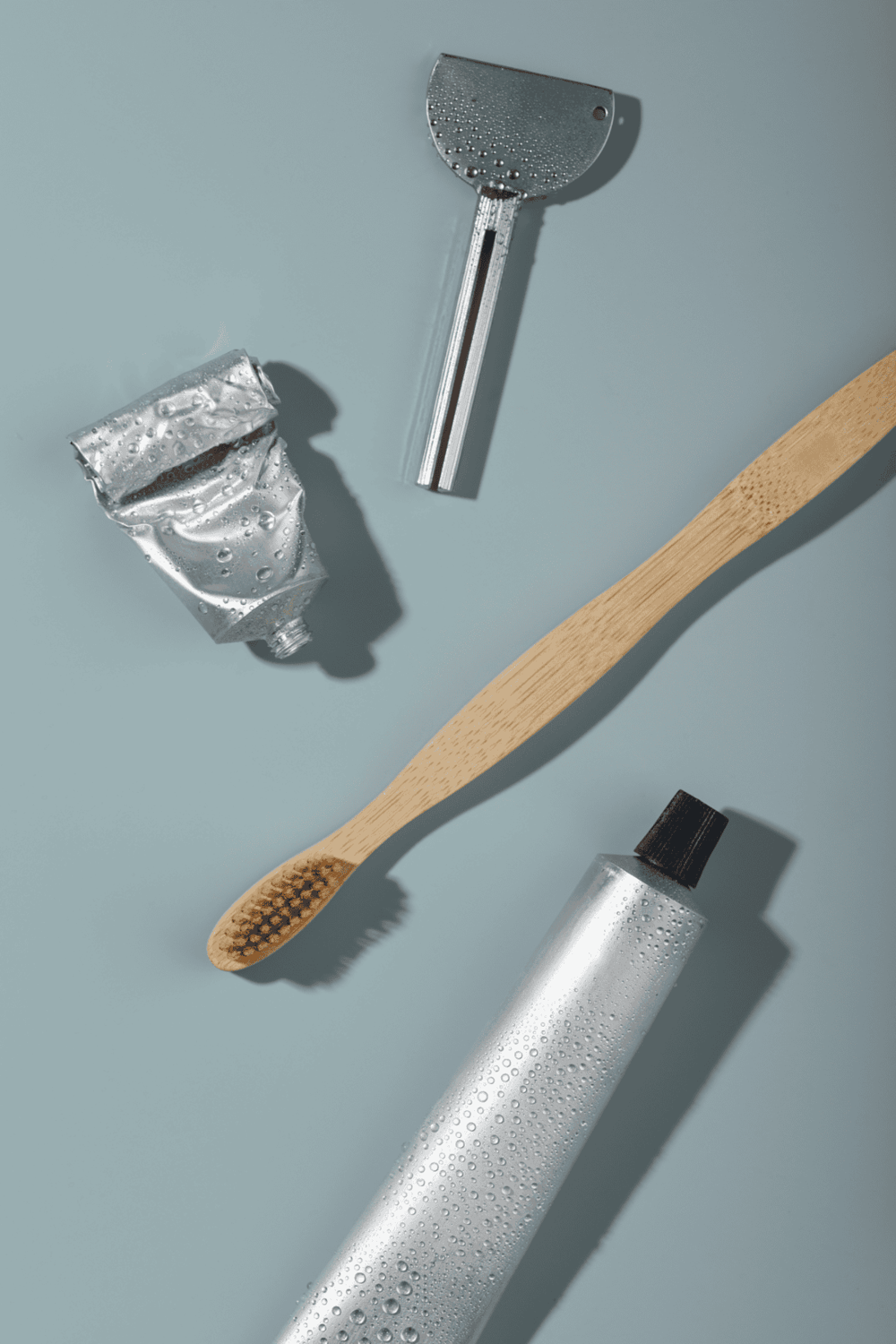 Moisturizer, bamboo toothbrush, razor, and skincare products on blue background for skincare routine.