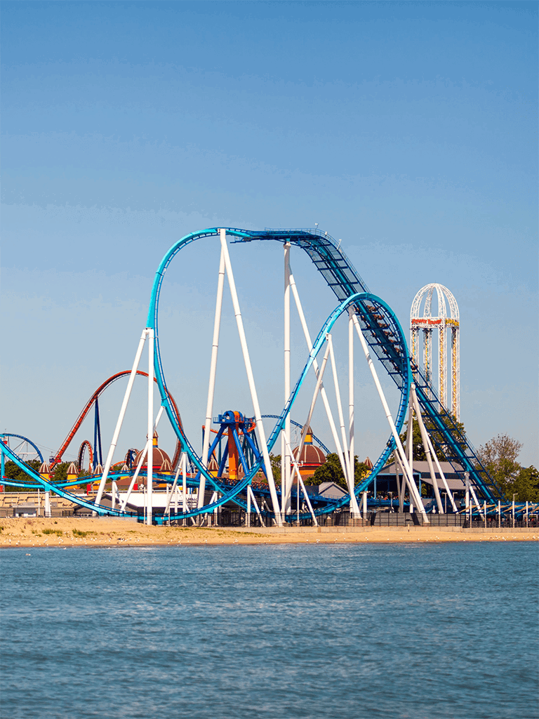 Thrilling roller coaster at Quest for Directions amusement park near water.