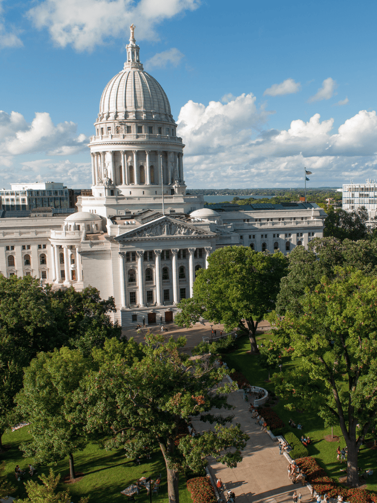 Dome of the Capitol building in Washington, D.C., with surrounding greenery and blue sky.