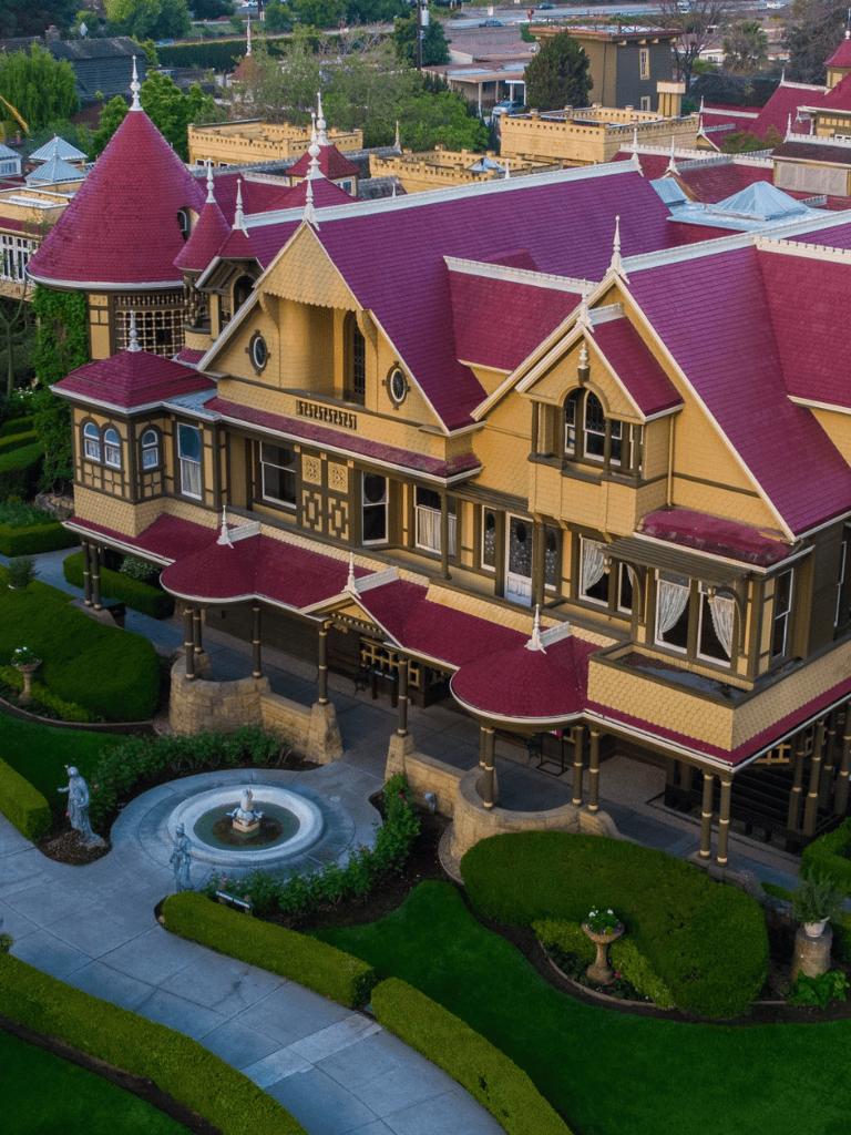 Elegant Victorian-style mansion with colorful turrets and lush landscaped gardens.