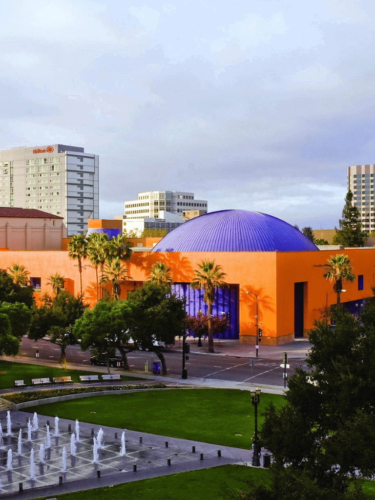 Colorful modern building in downtown with city skyline, fountains, and palm trees, part of Quest for Directions urban exploration.