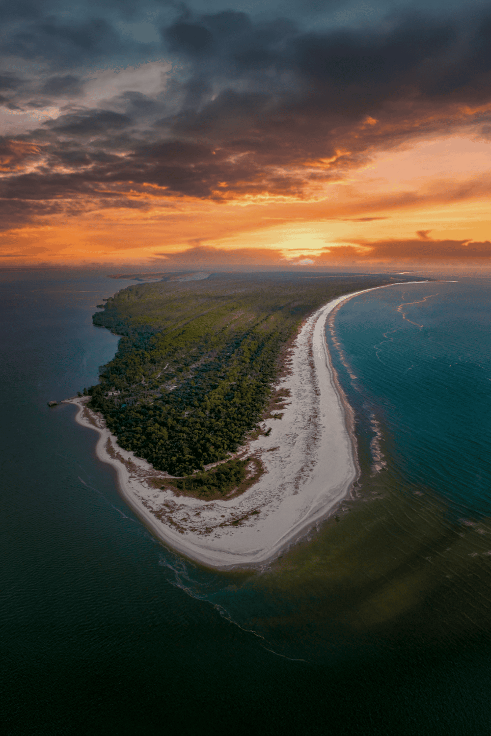 Secluded coastal island with lush greenery and pristine beaches at sunset.