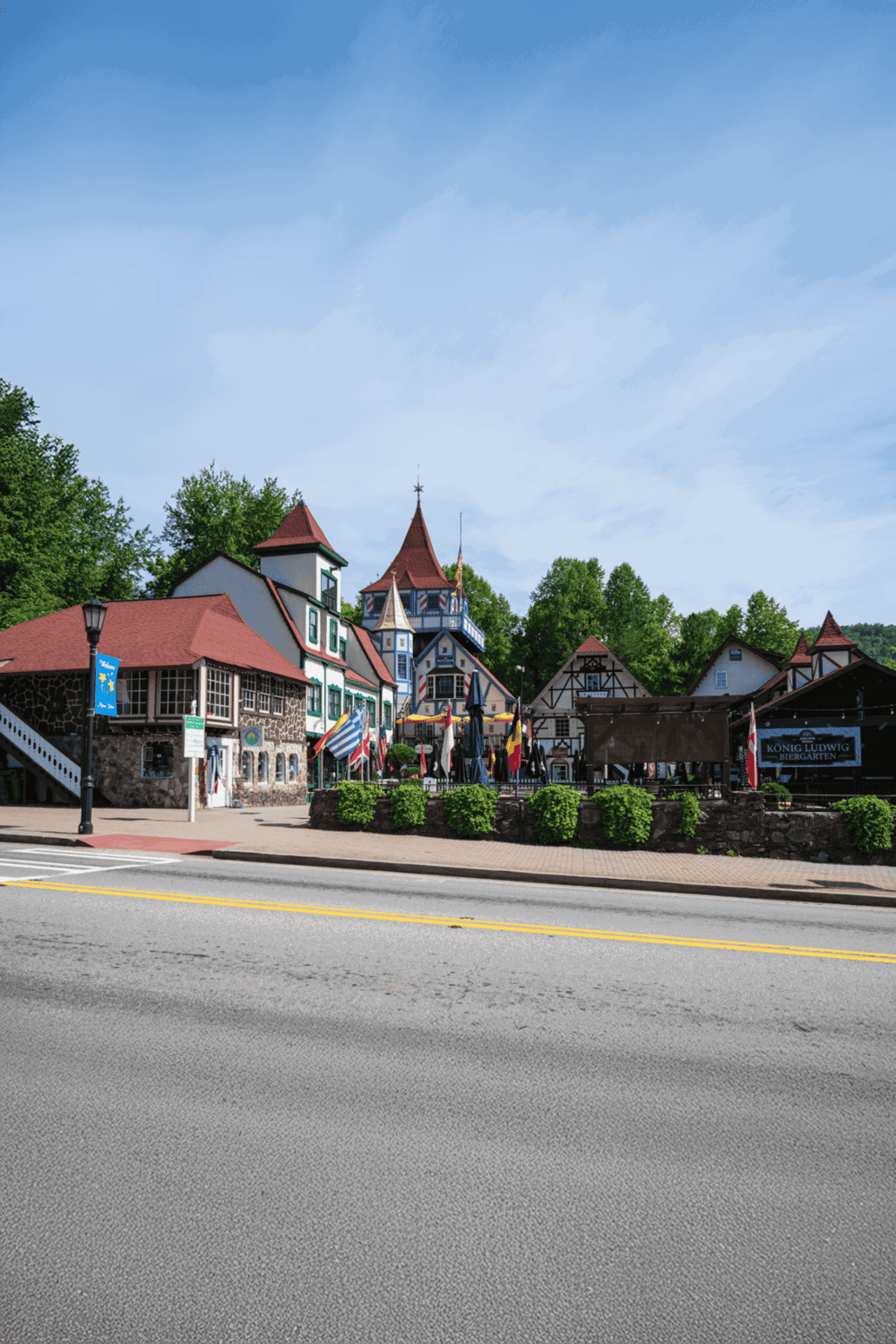 Colorful European-style buildings along scenic street with lush greenery in background.