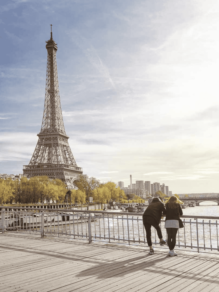 Eiffel Tower view in Paris with people enjoying the riverfront scenery.