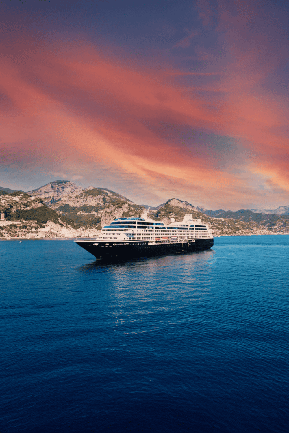 Luxurious cruise ship sailing in scenic blue waters during sunset.