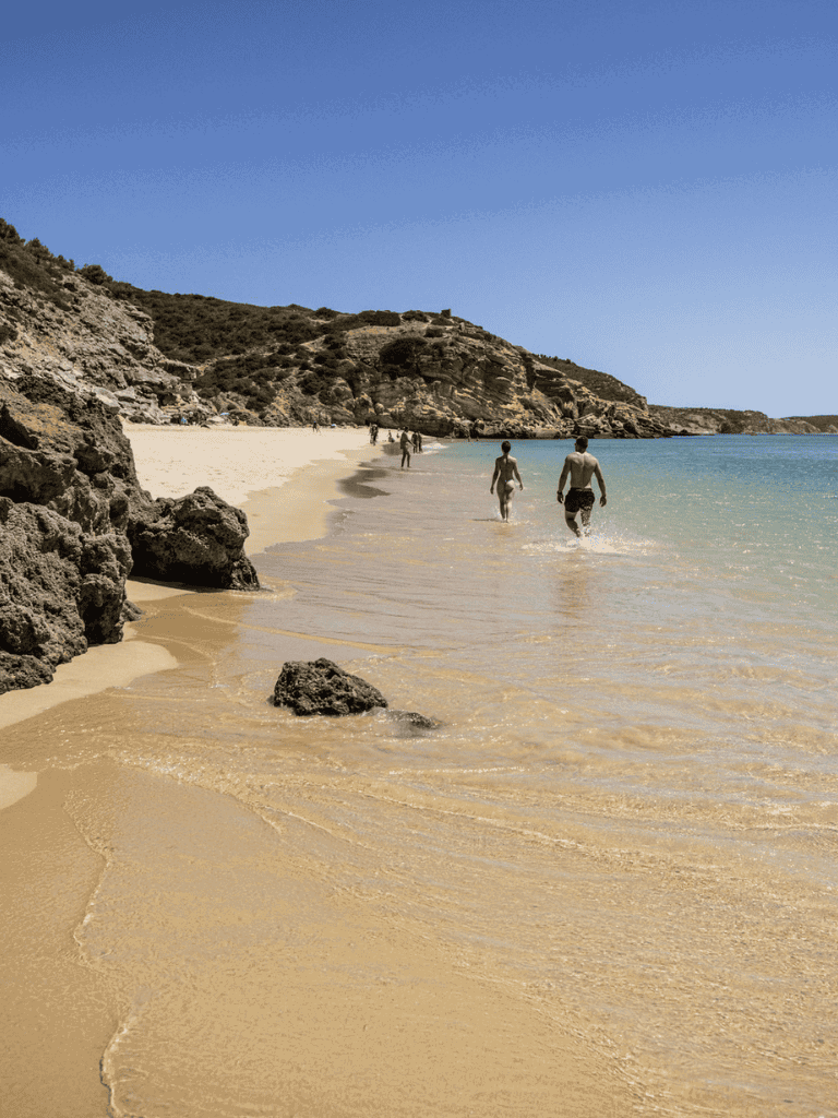 Pristine beach with rocky cliffs and clear blue water, perfect for relaxation and seaside adventures.