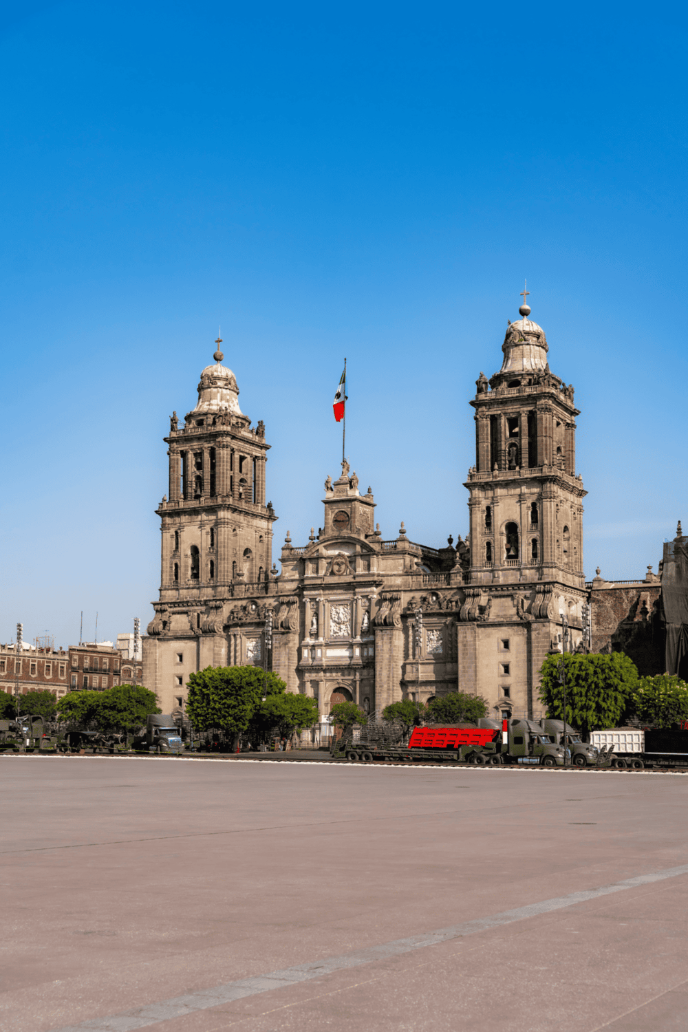 Majestic historic church with twin bell towers and Mexican flag in downtown Mexico City.