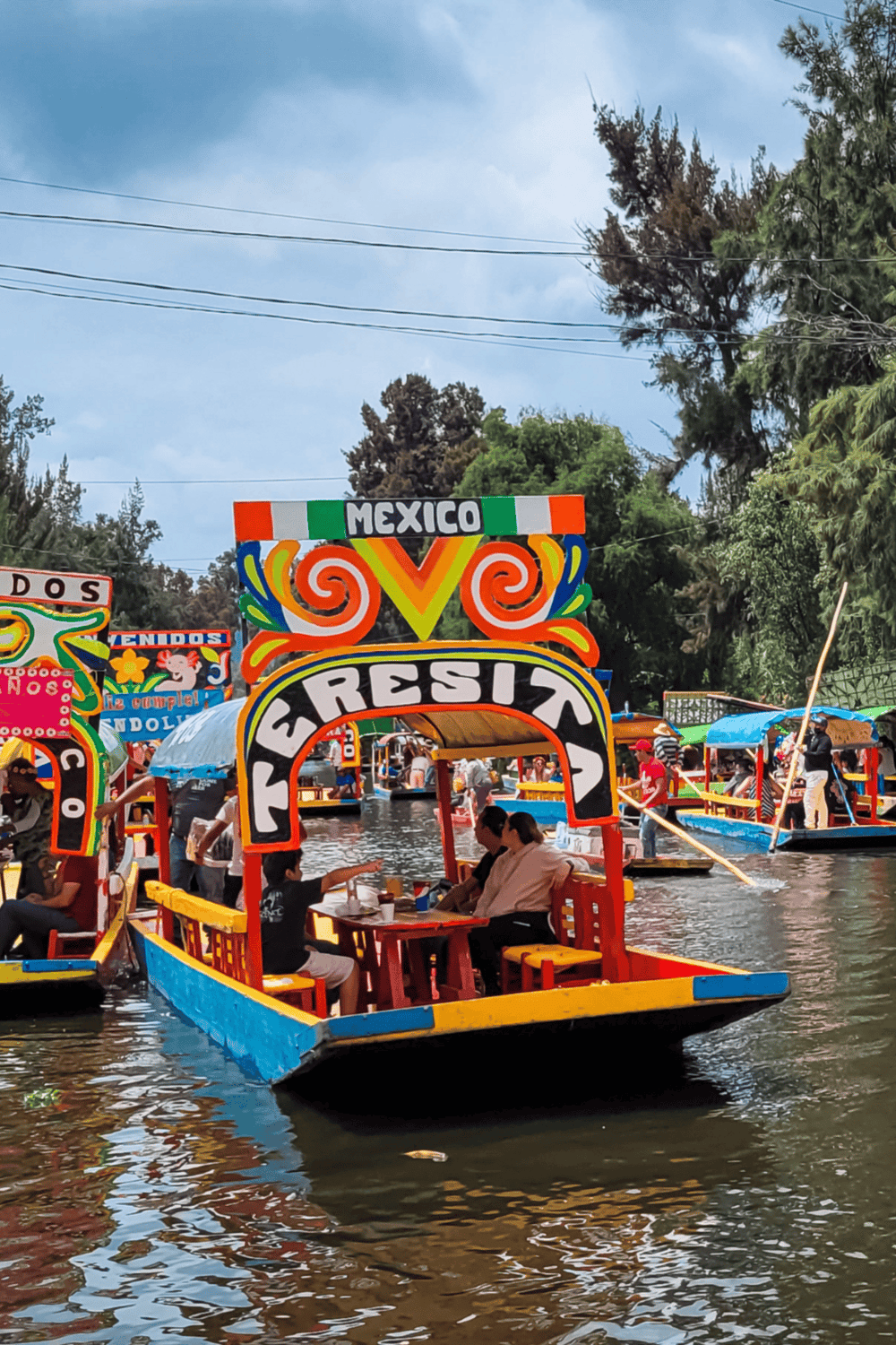 Colorful boat ride in Xochimilco, Mexico City, showcasing traditional trajineras and vibrant canal scenery.