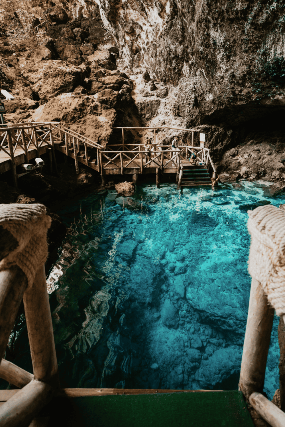 Vivid underground cave with turquoise water and wooden walkway for guided tours.