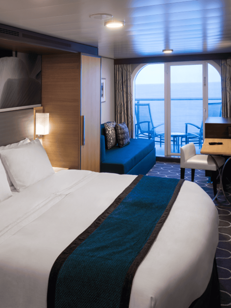 Comfortable cruise ship bedroom with ocean view and balcony access, perfect for relaxation.