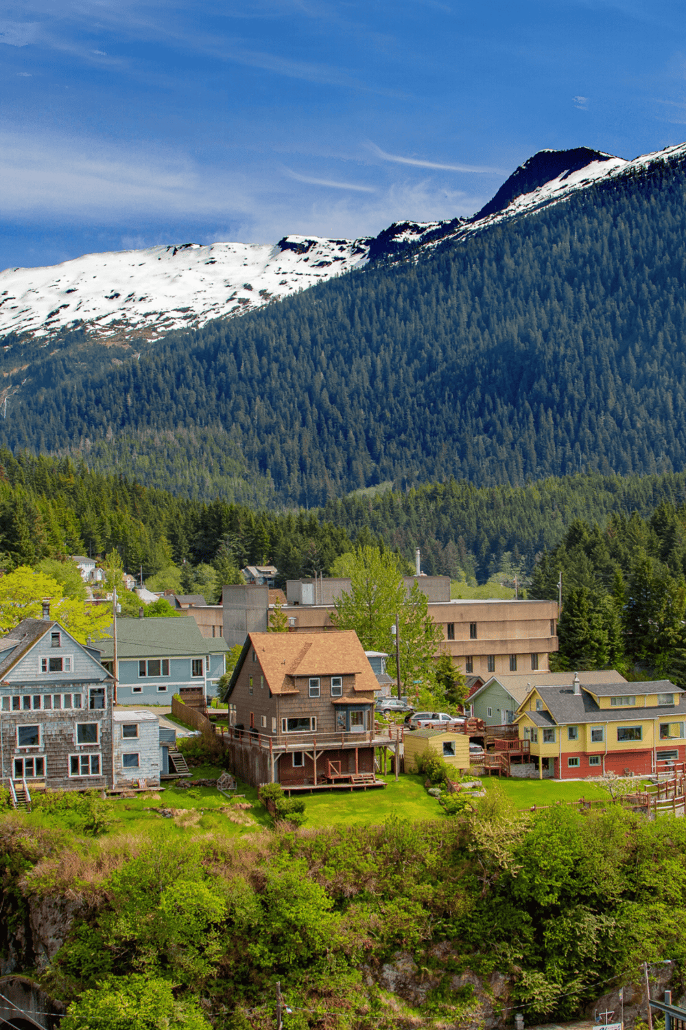 Scenic mountain village with colorful houses and lush greenery under a snow-capped peak.