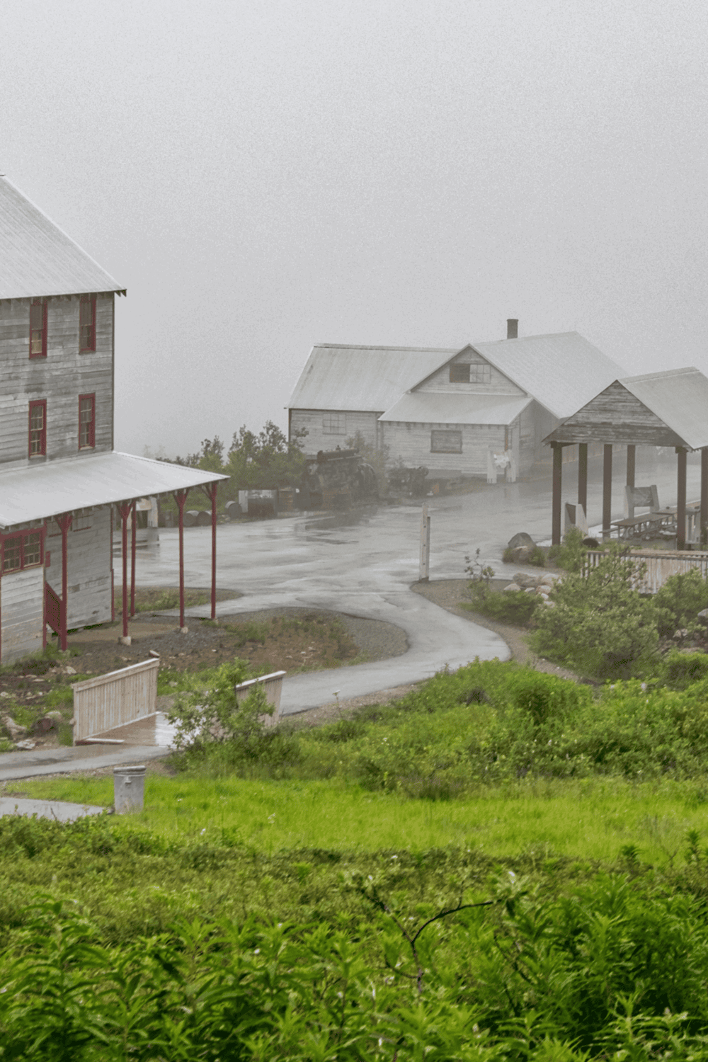 Old rustic buildings on a foggy mountain in a rural setting.