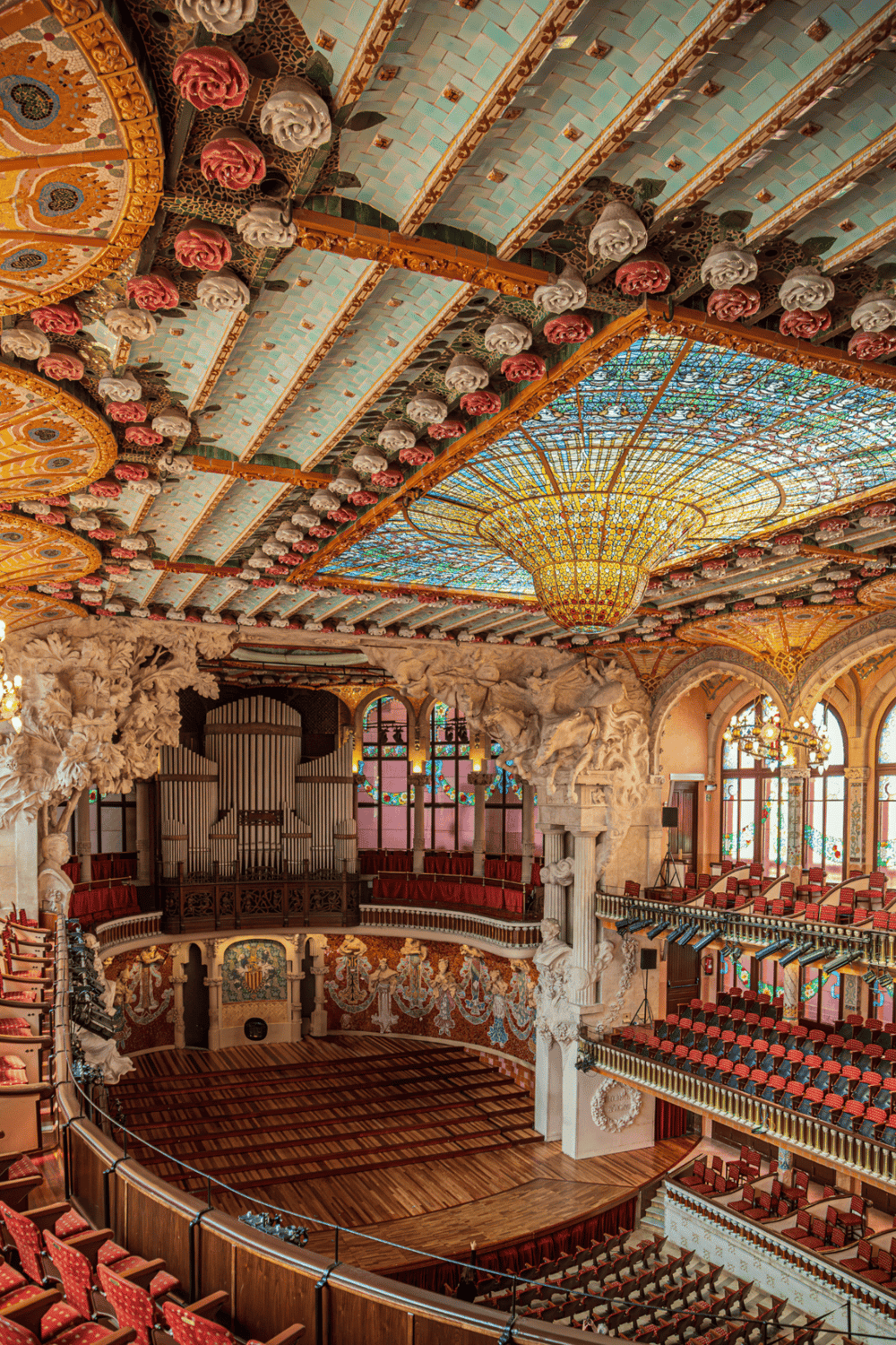 Luxurious theater interior with ornate ceiling and stained glass chandelier.