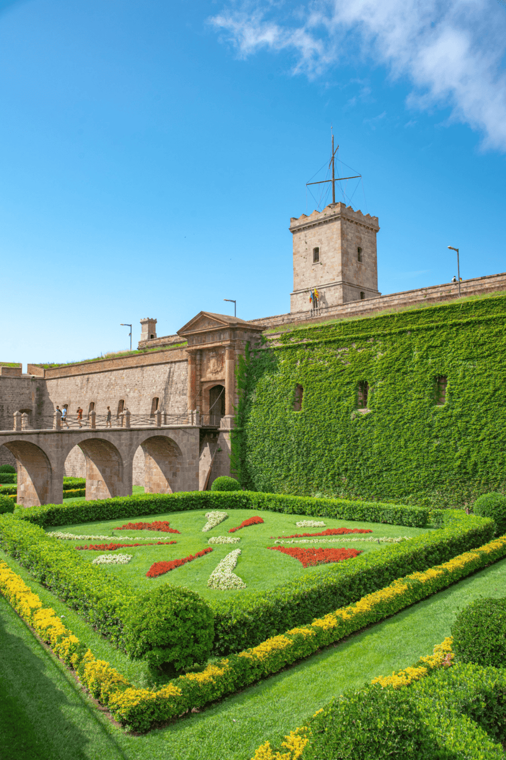 Historic castle fortress with vibrant floral garden, lush green ivy walls, and scenic panoramic views, perfect for travel and sightseeing.