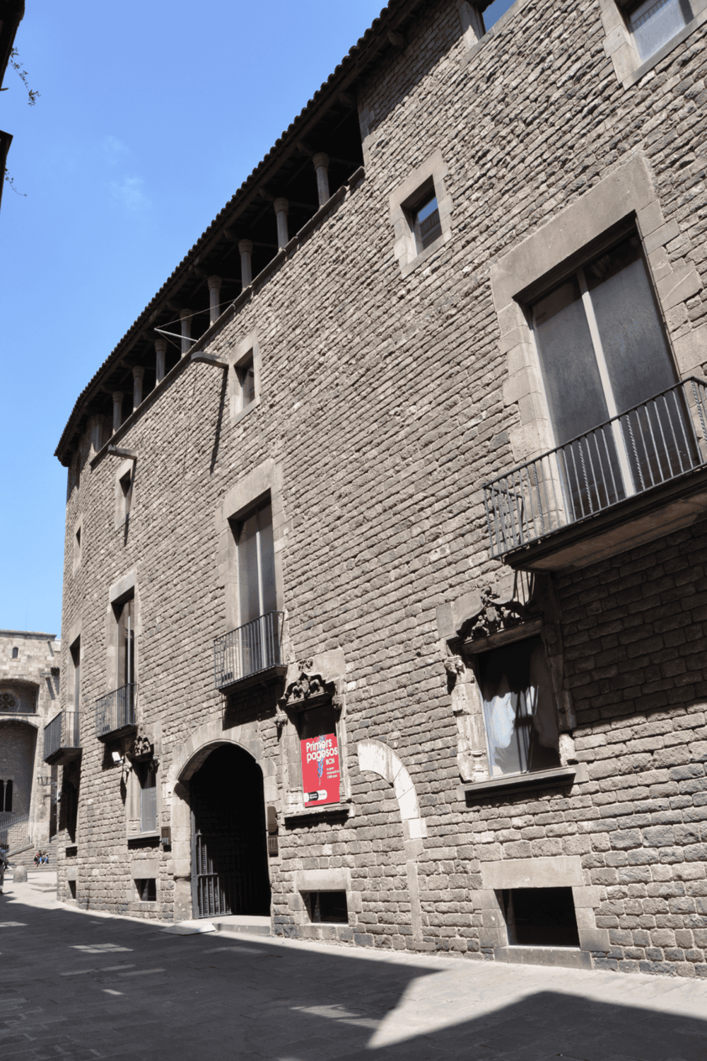 Ancient stone building with small balconies and narrow windows, Barcelona historical architecture.