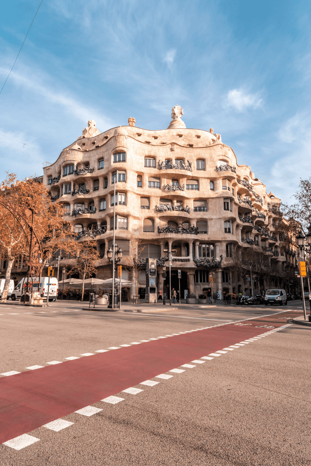 1. Unique modernist building on a city street with leafless trees and traffic lights.