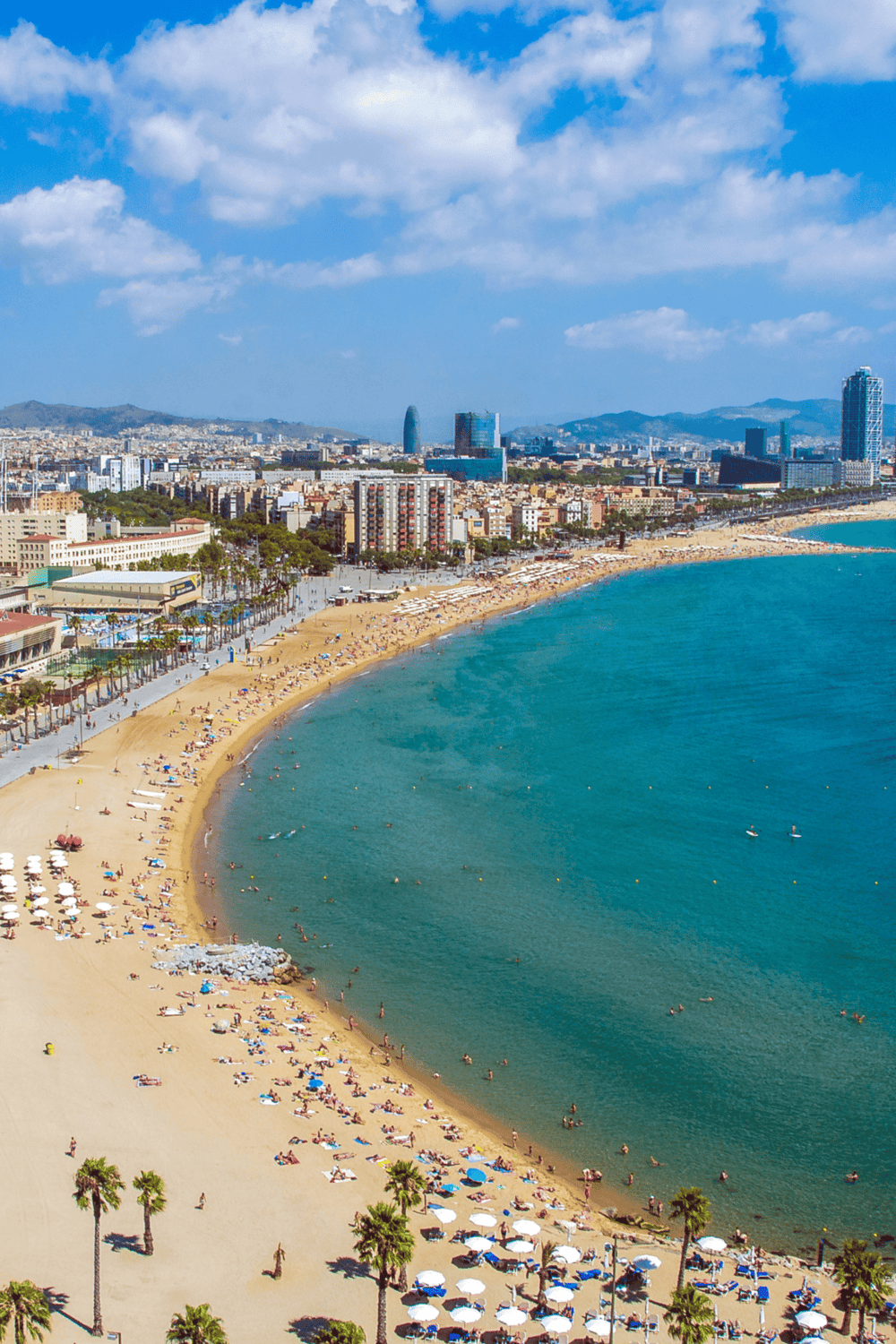Breathtaking view of Barcelona beach with city skyline, mountains, and blue sea, perfect for travel and tourism inspiration.