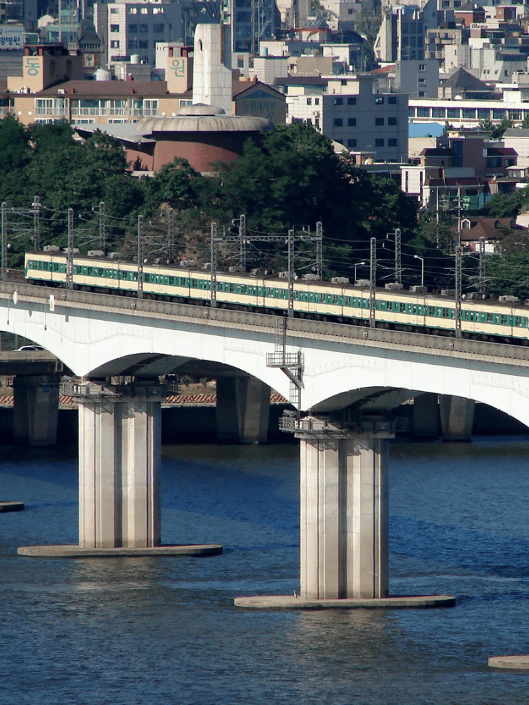 Green commuter train crossing a bridge over a river in Seoul, South Korea.