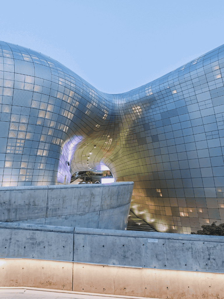 Bright, futuristic architectural building with reflective glass exterior and innovative curved design.