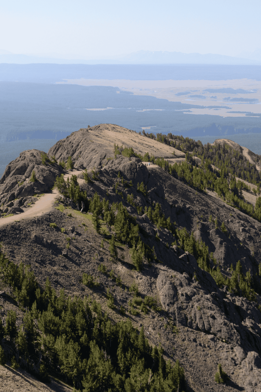 Majestic mountain peak with hiking trail and lush green trees, offering scenic views and outdoor adventure.