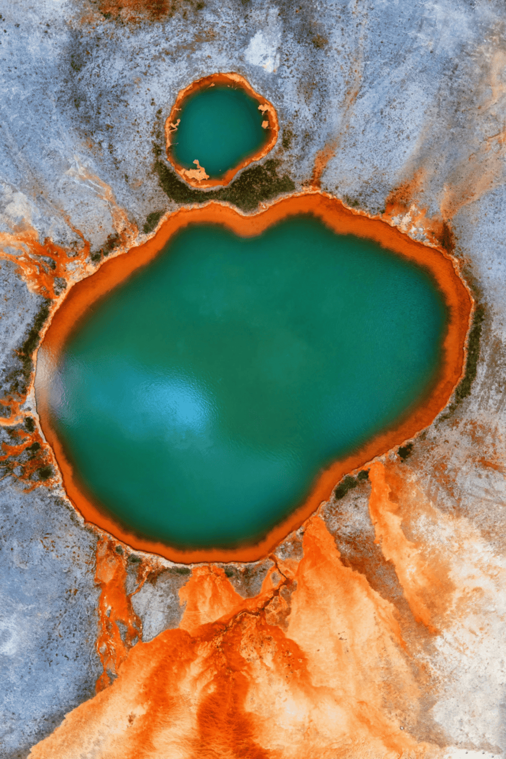 Vivid aerial view of colorful geothermal hot springs with orange, green, and blue waters, showcasing natural mineral formations.