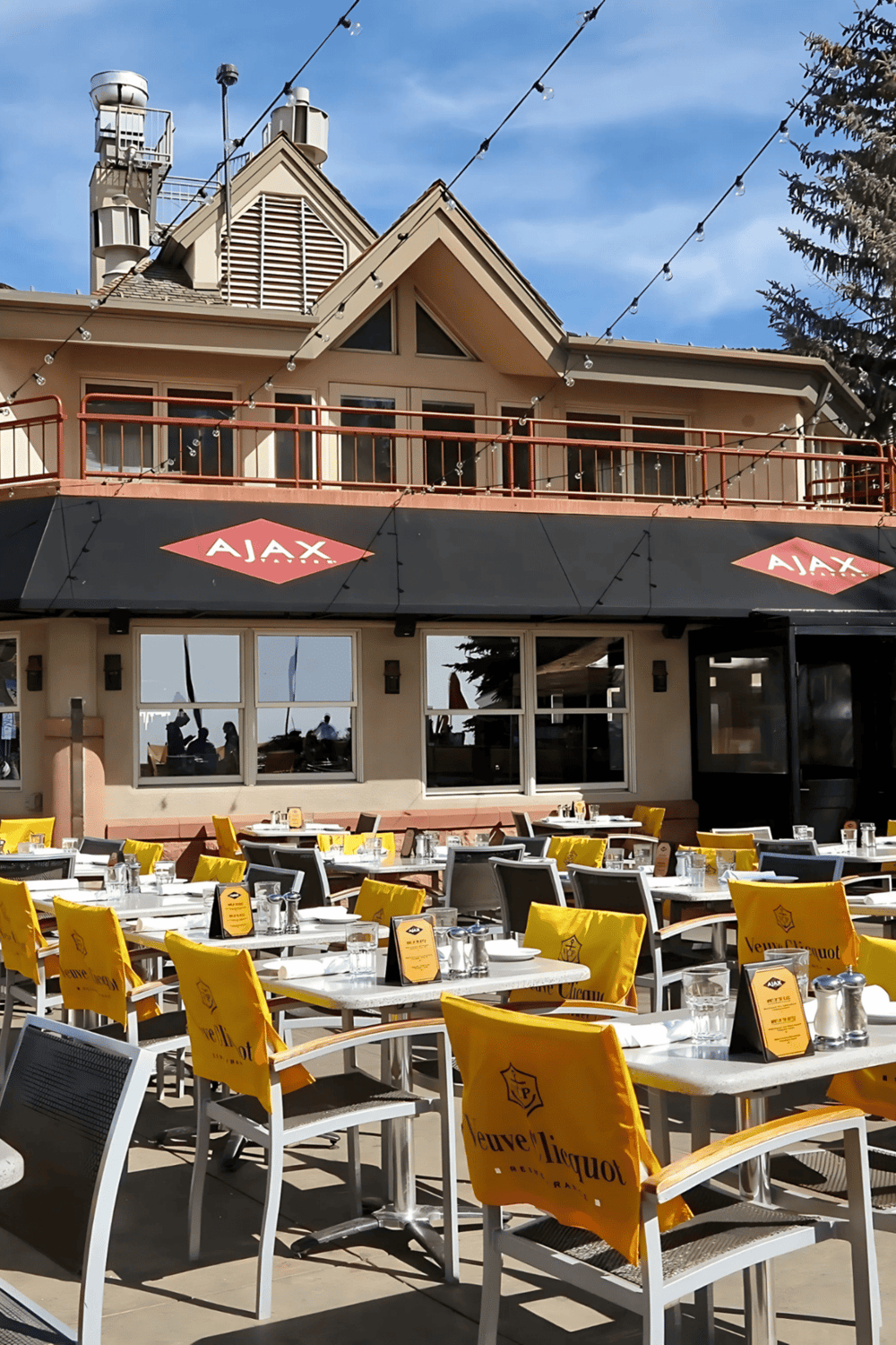 Alto text: Downtown restaurant patio with outdoor seating and AJAX signage under string lights.