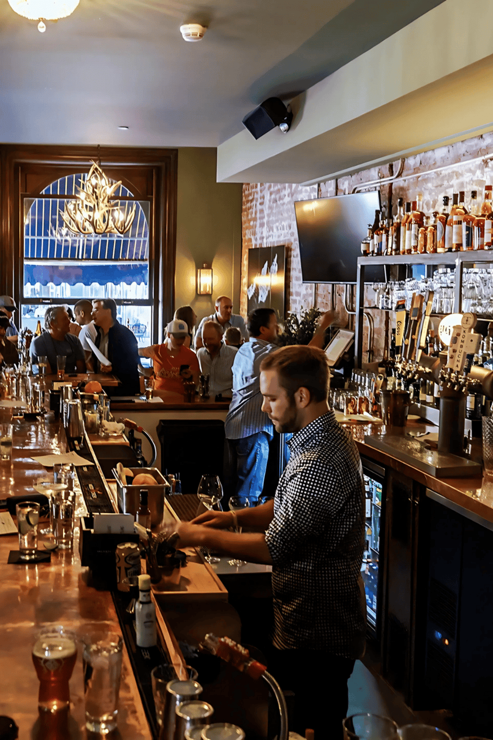 Bartender preparing drinks at a lively bar in a trendy restaurant or pub.