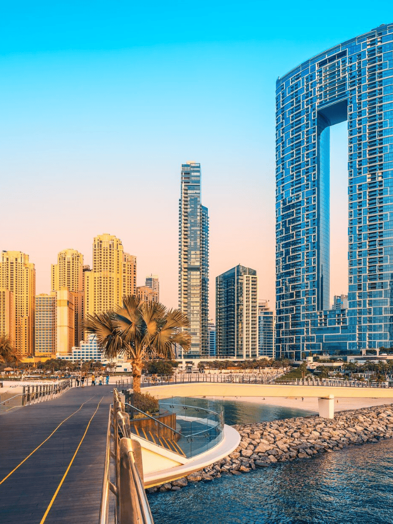 Bright city skyline with modern skyscrapers and waterfront at sunset.