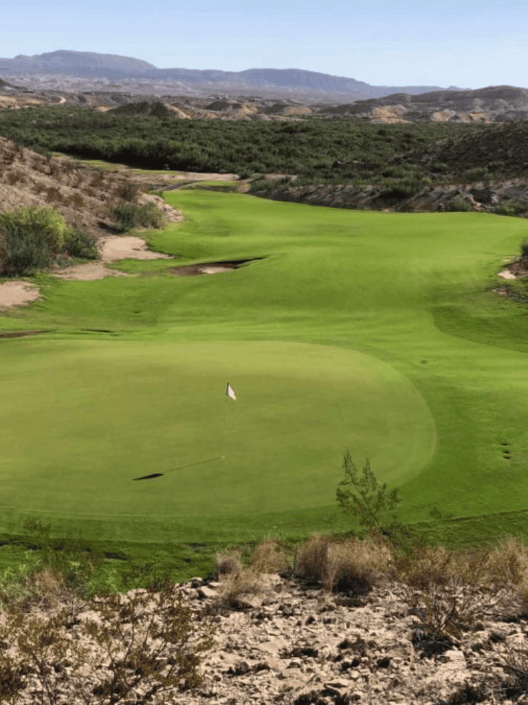 Lush green golf course landscape with rolling hills and desert terrain, perfect for outdoor golf adventures.