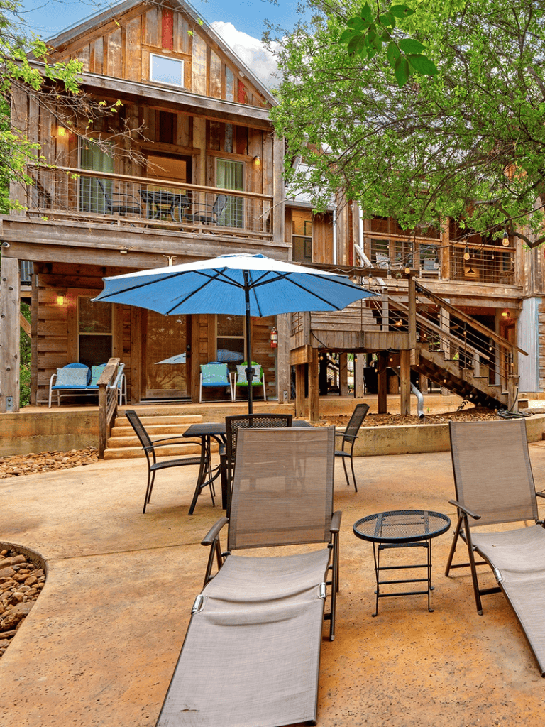 Charming rustic cabin with outdoor seating and lush greenery, ideal for vacation rentals and nature escapes.
