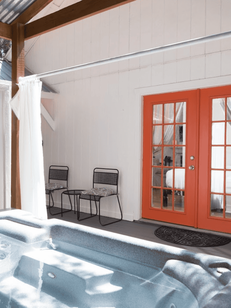 Outdoor hot tub with orange French doors and cozy seating area, perfect for relaxation and outdoor living.