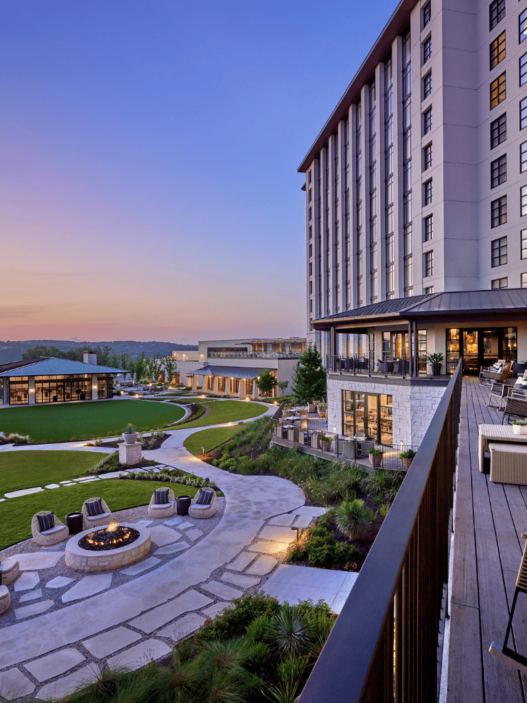 Luxury hotel rooftop terrace with city views and outdoor seating at sunset.