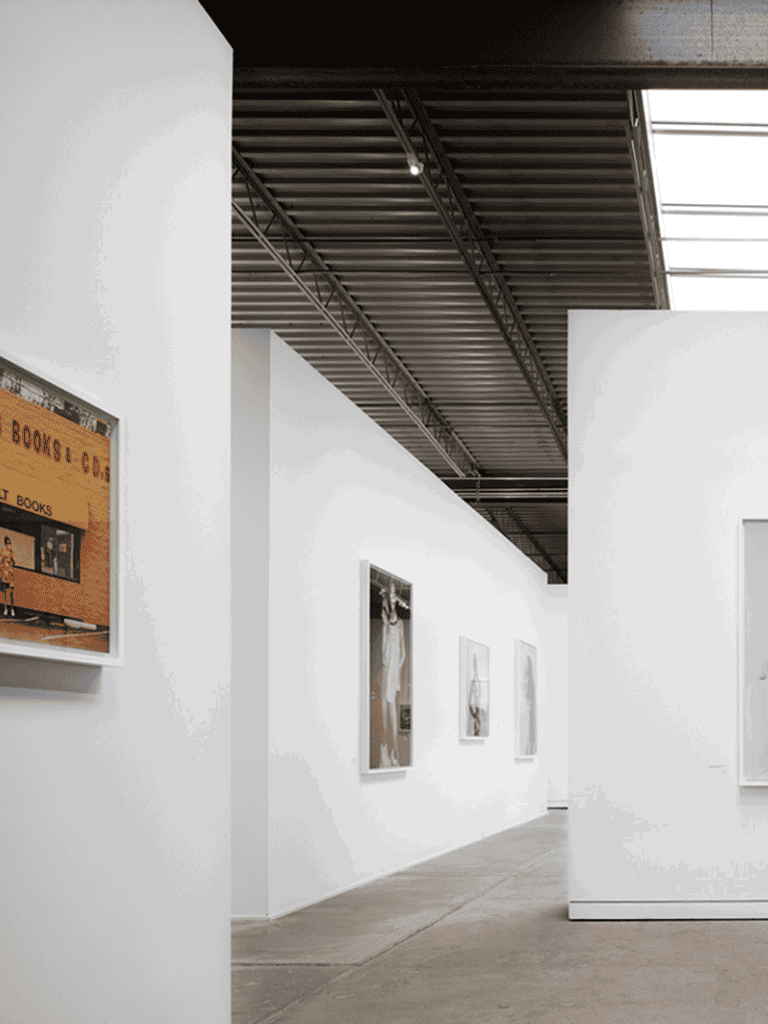 Aisle view of contemporary art gallery at QuestForDirections exhibition space, clean white walls.