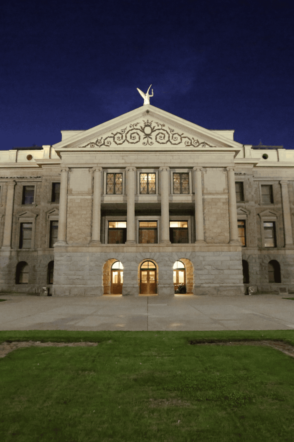 Ancient Greek Revival courthouse illuminated at night with classic columns and decorative reliefs.