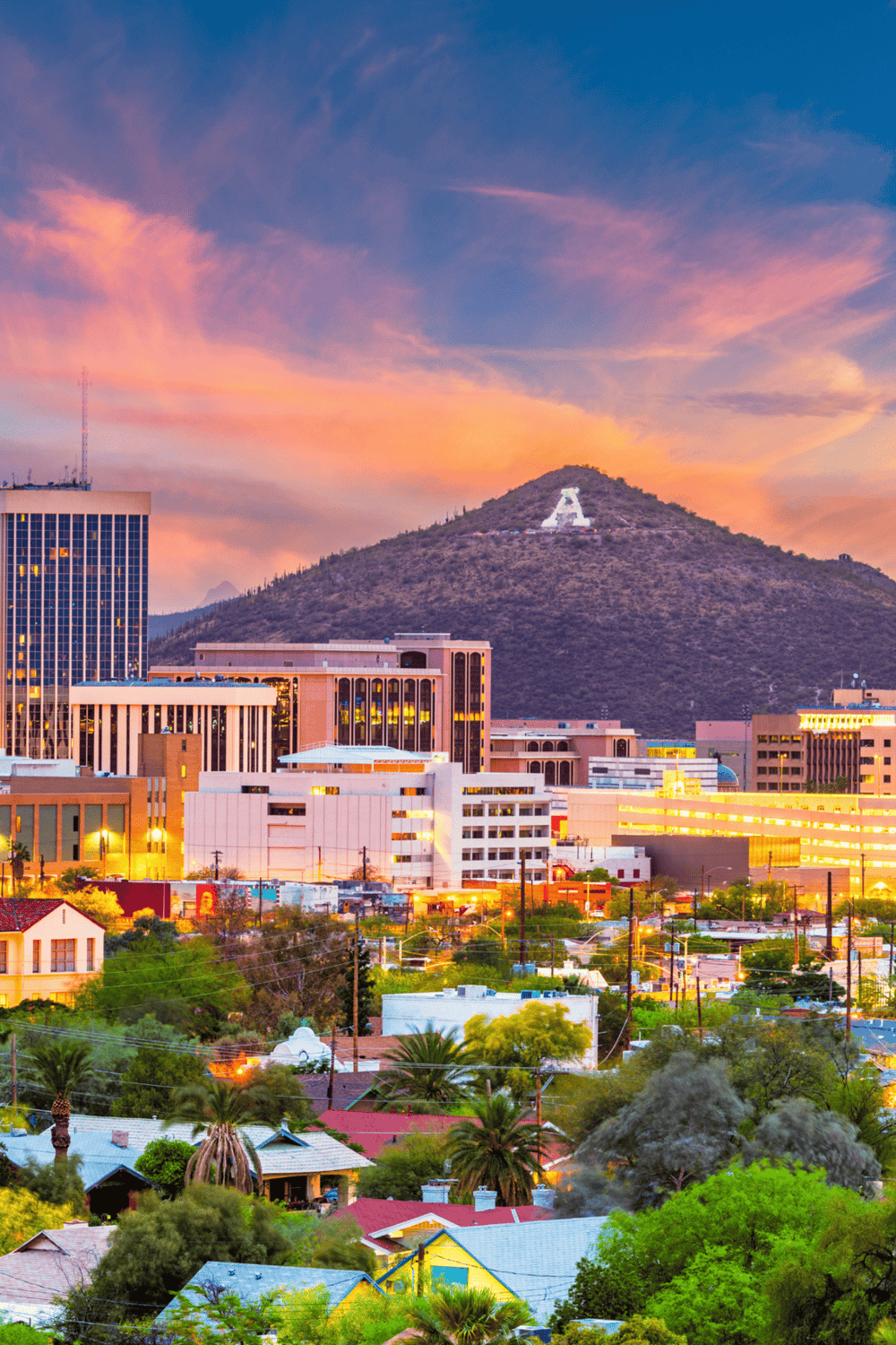 Vibrant cityscape of Phoenix at sunset with mountains and the iconic Phoenix sign on Camelback Mountain.