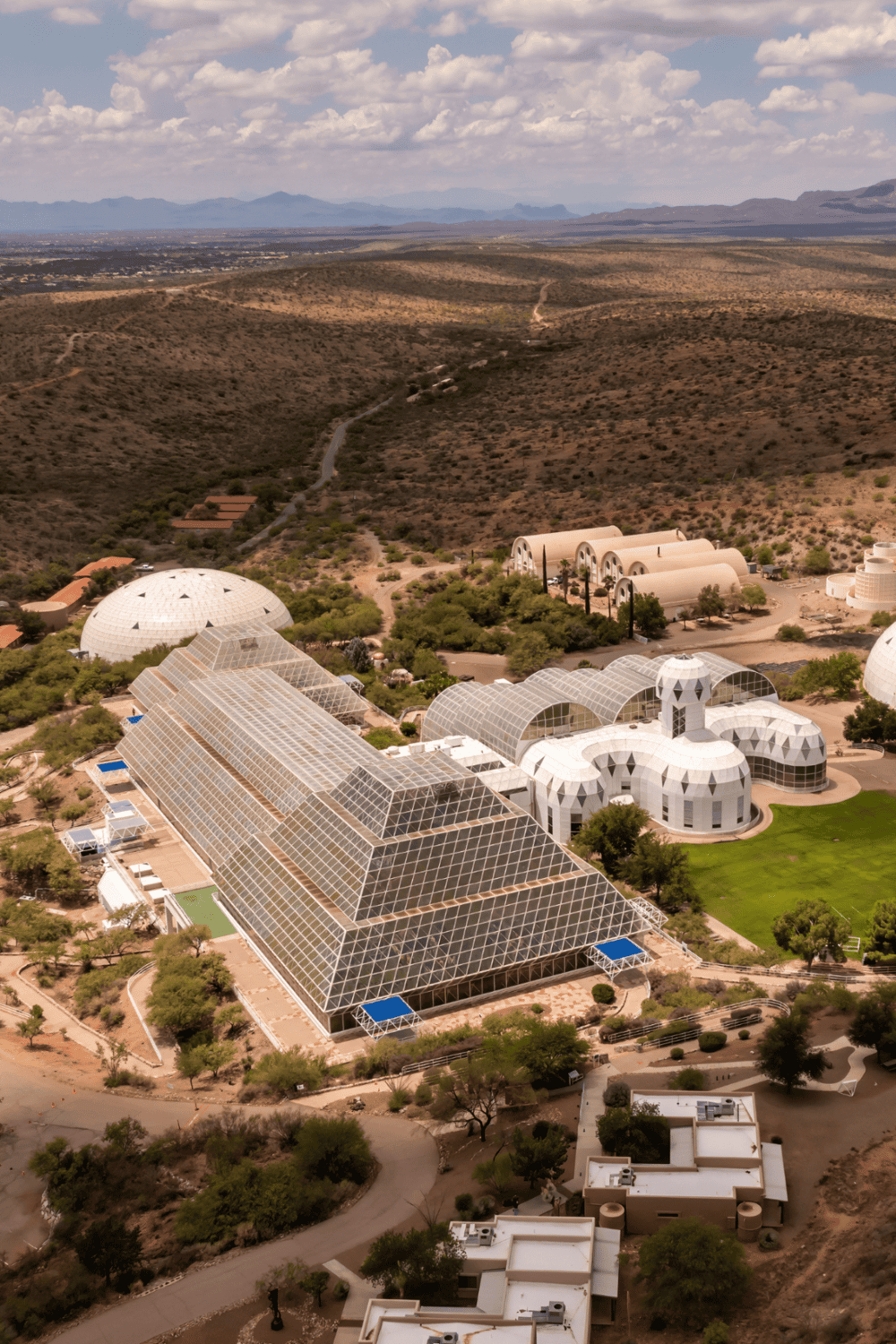 Modern desert botanical gardens with glass structures and mountain views.