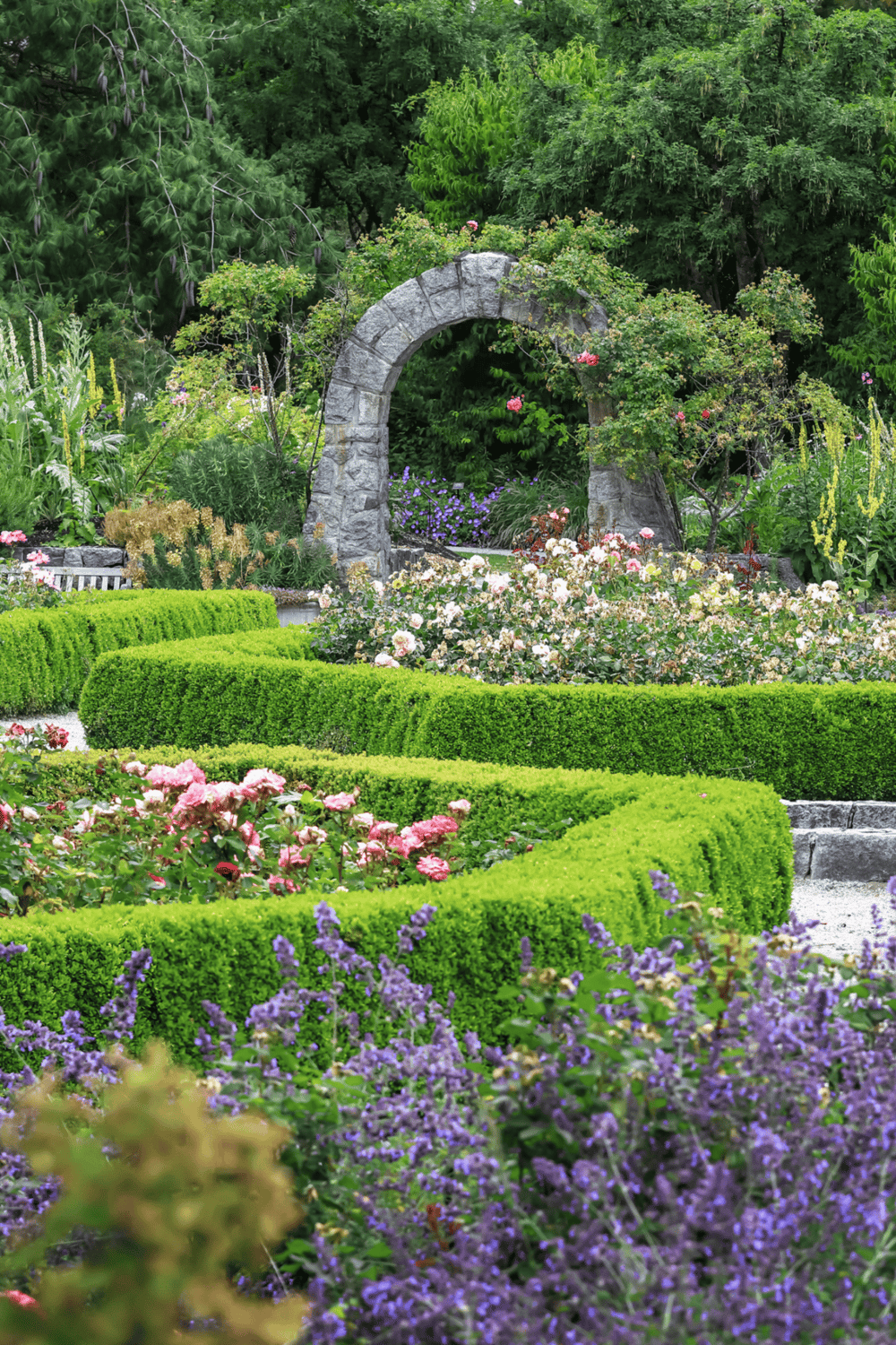 Colorful garden with stone arch and lush greenery for peaceful landscape design.
