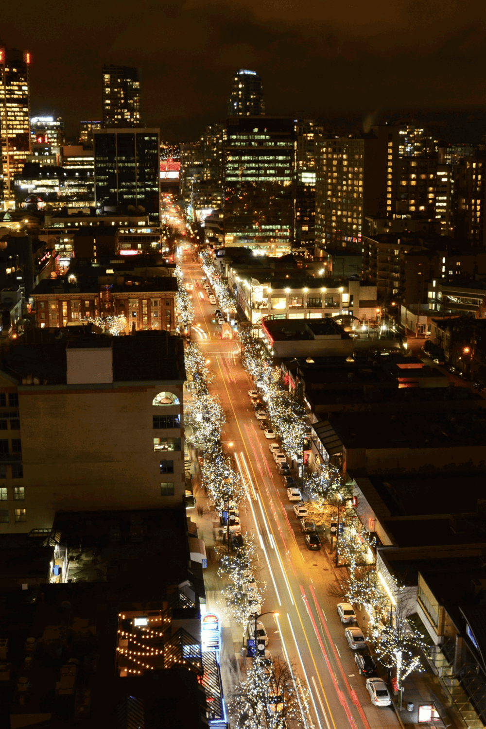 Bright city nightlife with illuminated streets and modern high-rise buildings in downtown urban area.