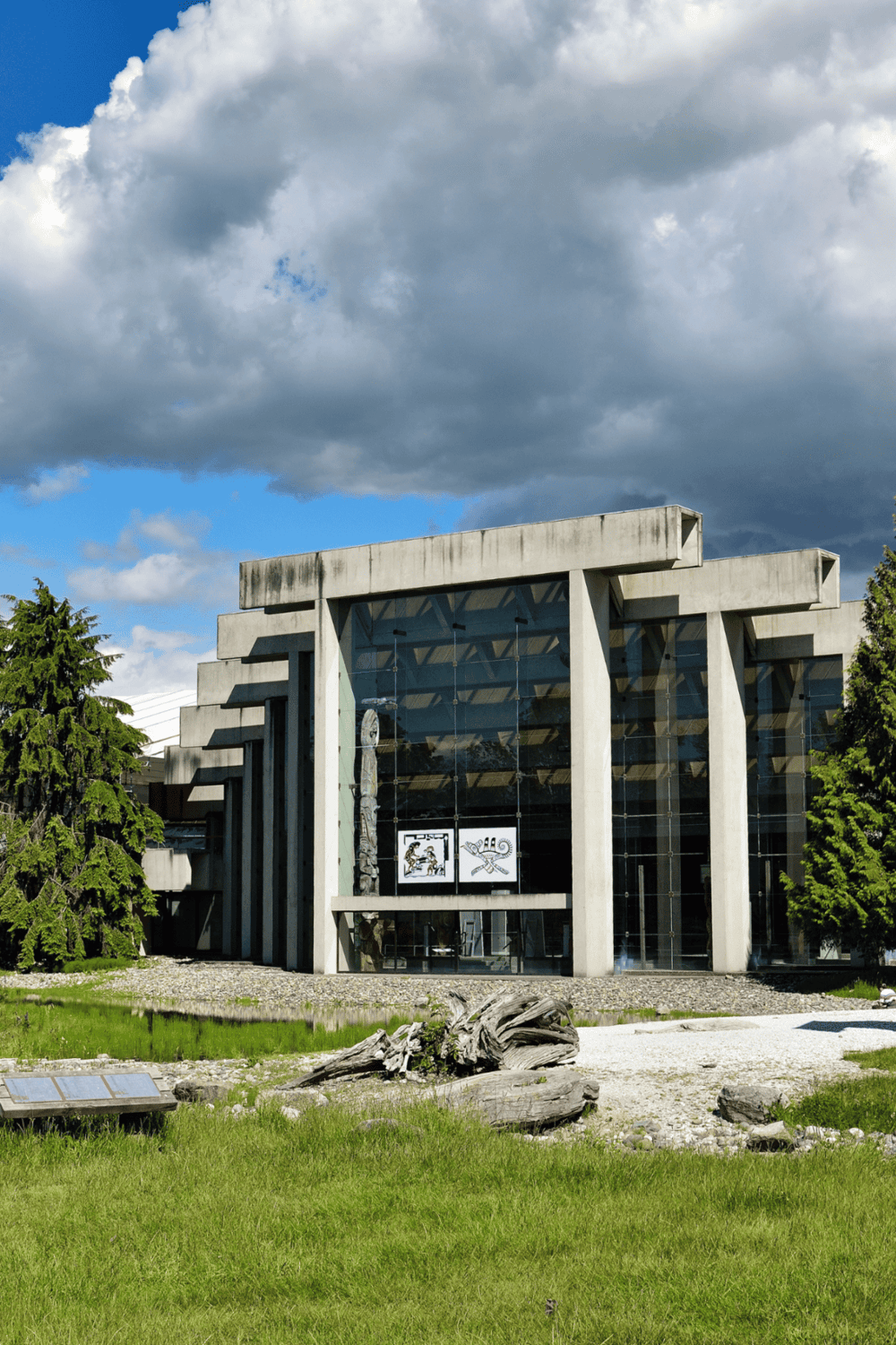 Contemporary architecture building with concrete and glass design, set against a dramatic cloudy sky.