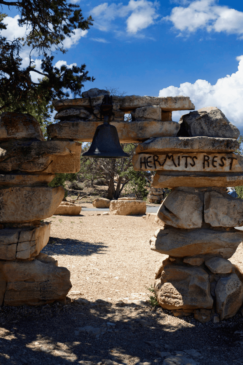 1. Rustic stone archway with bell at Hermits Rest, scenic desert landscape in the background.