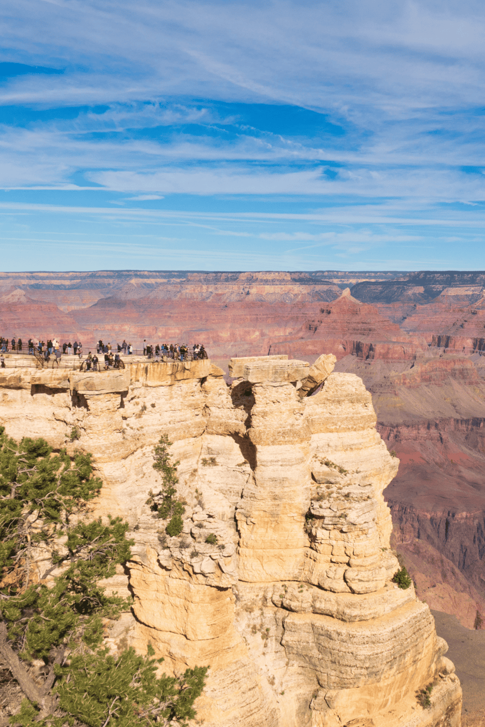 Bright blue sky over Grand Canyon with tourists viewing edge, showcasing adventure and sightseeing in Arizona.