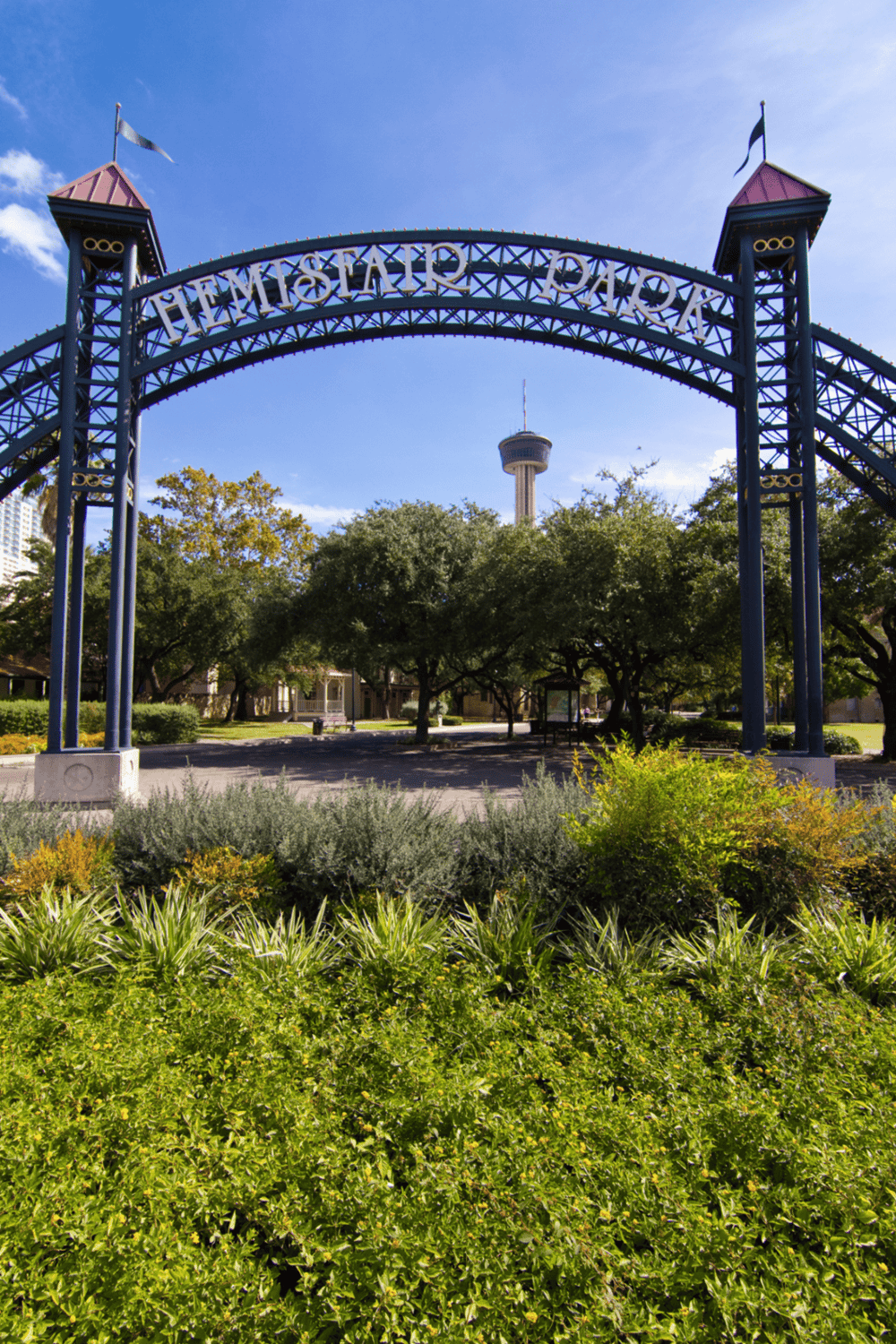 Historic Fairfield Park entrance with lush greenery and the Stratosphere Tower in the background, showcasing outdoor attractions in Las Vegas.