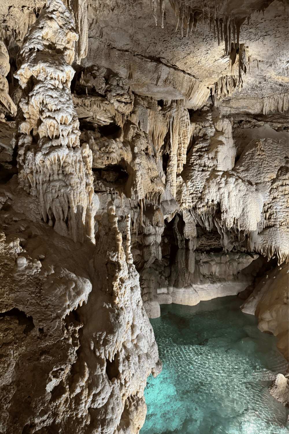Intricate limestone cave formations with underground water pool in adventure tourism destination.
