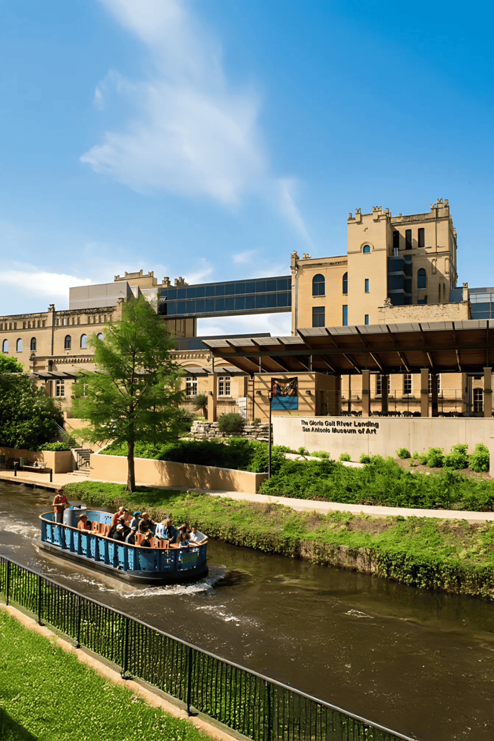 Historic San Antonio riverwalk with boat tour, modern architecture, and lush greenery.