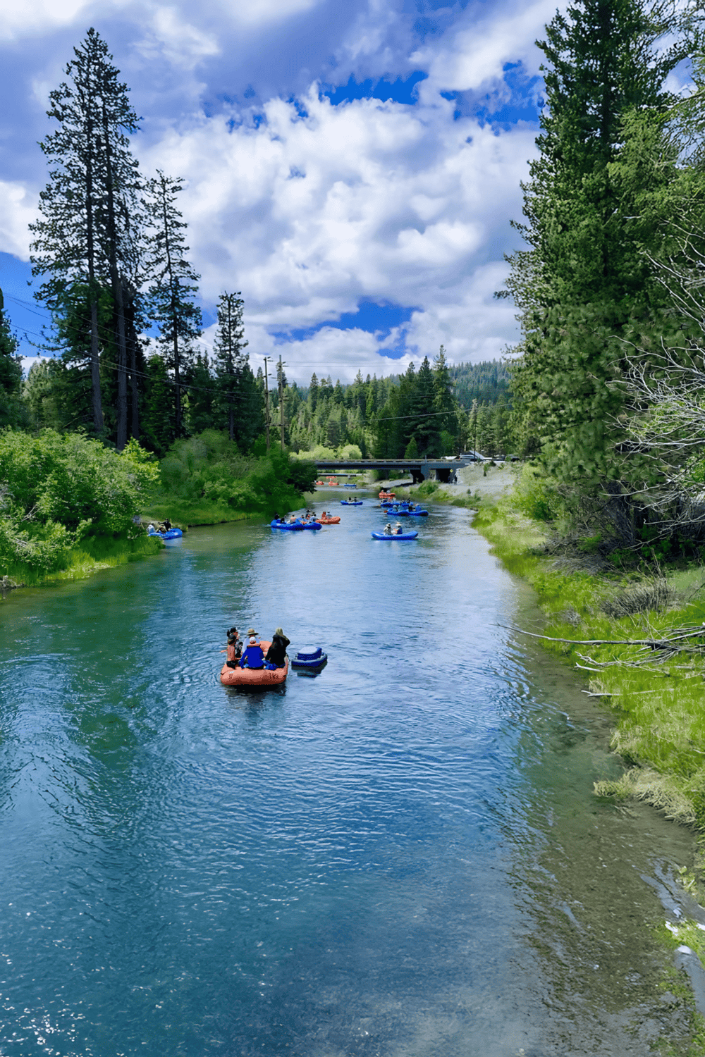 Beautiful river with paddle boats surrounded by lush green trees under a partly cloudy sky at QuestForDirections.